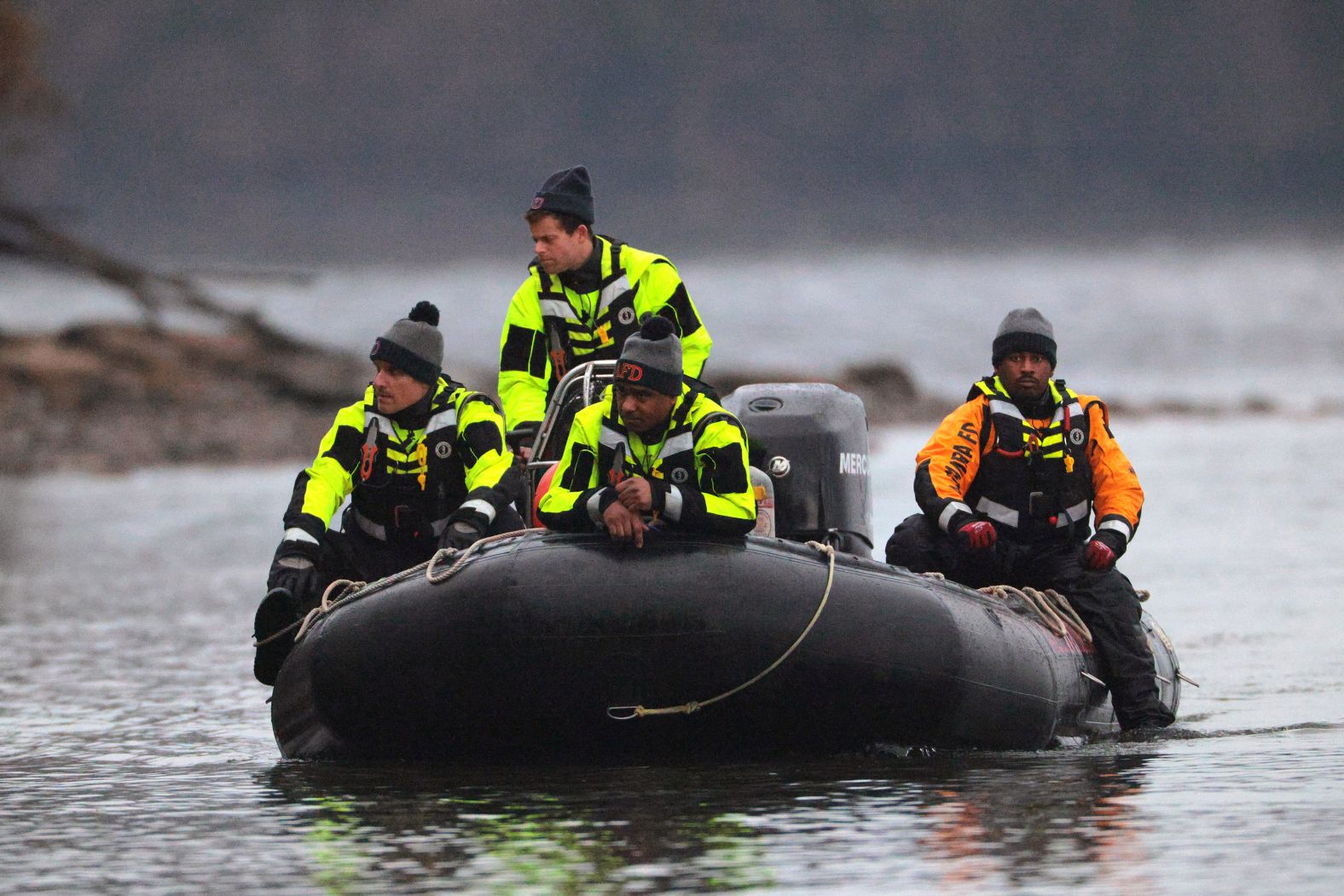 Members of the Alexandria Fire Department look for aircraft debris along the shoreline of the Potomac River on Friday.