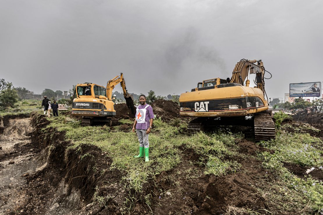 A member of the Congolese Red Cross stands next to earth-moving machines at a graveyard in Goma on February 4, 2025, where fresh graves have been dug.