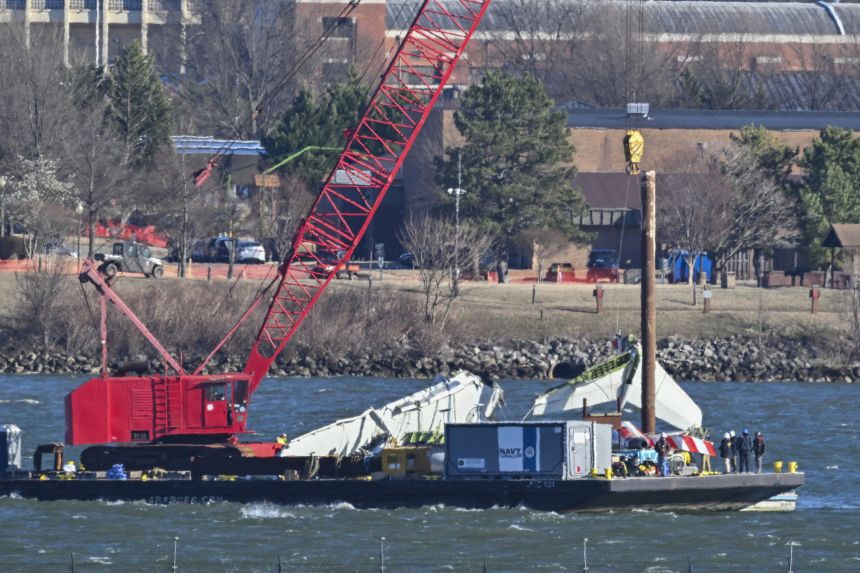 US Navy recovery teams lift the back wing section of an American Airliners plane from the Potomac in Arlington, Virginia on February 4, 2025. Operations to salvage the wreckage from a deadly collision between a US Army helicopter and a passenger jet continued as rescuers said 55 victims had so far been identified. Dozens of victims have been pulled from the icy Potomac River, and rescuers voiced confidence that those remaining would be retrieved in the massive operation to recover the plane that collided in midair with a Black Hawk military helicopter. (Photo by ROBERTO SCHMIDT / AFP) (Photo by ROBERTO SCHMIDT/AFP via Getty Images)