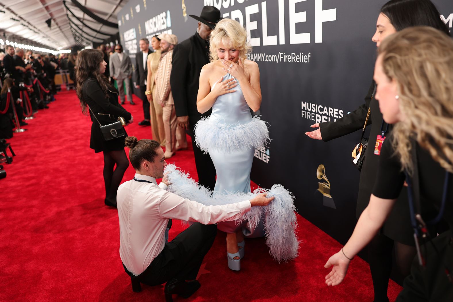 Sabrina Carpenter has her dress adjusted on the red carpet.