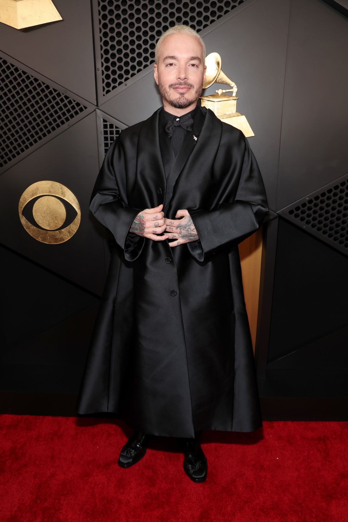 La tenue Dior Men de J Balvin comprenait un manteau en soie, une soie de smoking en laine, une chemise, un nœud papillon et des derbies en cuir - le tout en noir.