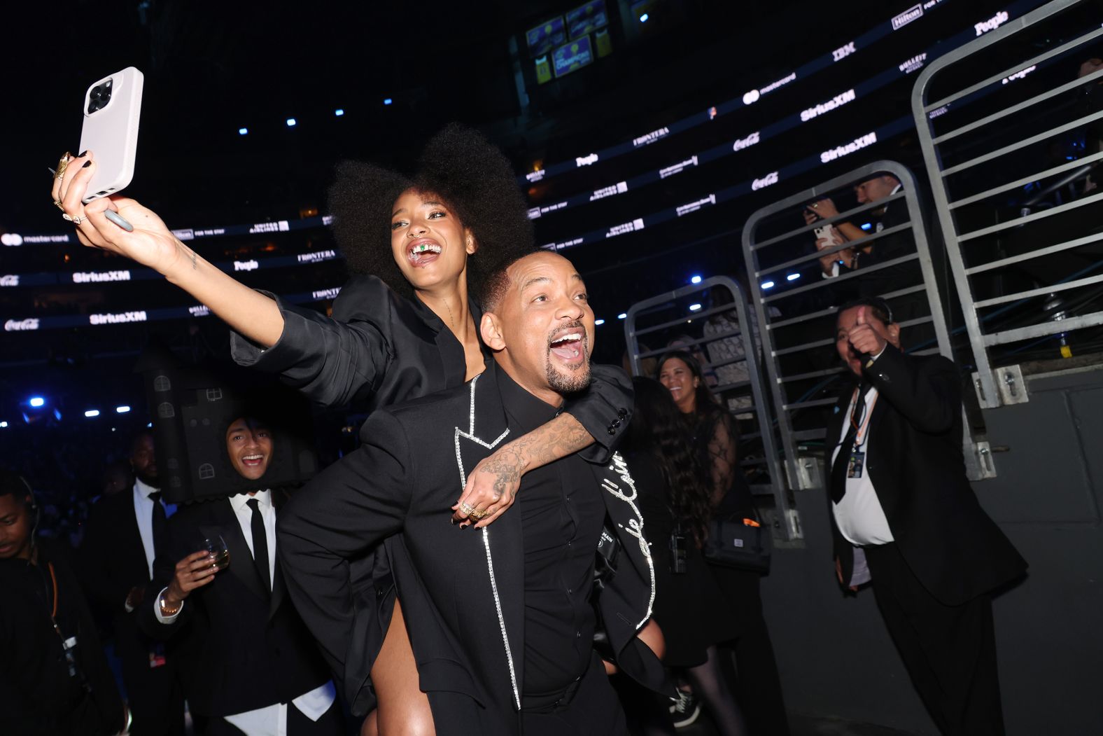 Willow Smith rides on the back of her father, Will, as they enjoy the show.