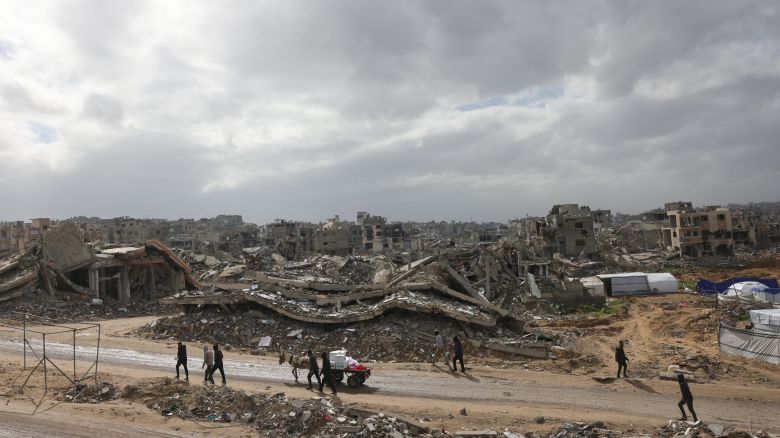 TOPSHOT - Palestinians use donkey carts for transport on roads lined up with heavily damaged buildings in Jabalia in the northern Gaza Strip on February 6, 2025 during a truce in the war between Israel and Hamas. In hunger-stricken makeshift shelters set up in former schools, bombed-out houses and cemeteries across the Gaza Strip, devastated by 15 months of war between Hamas and Israel, hundreds of thousands lack even plastic sheeting to protect from winter rains and biting winds, aid workers say. (Photo by Bashar TALEB / AFP) (Photo by BASHAR TALEB/AFP via Getty Images)          