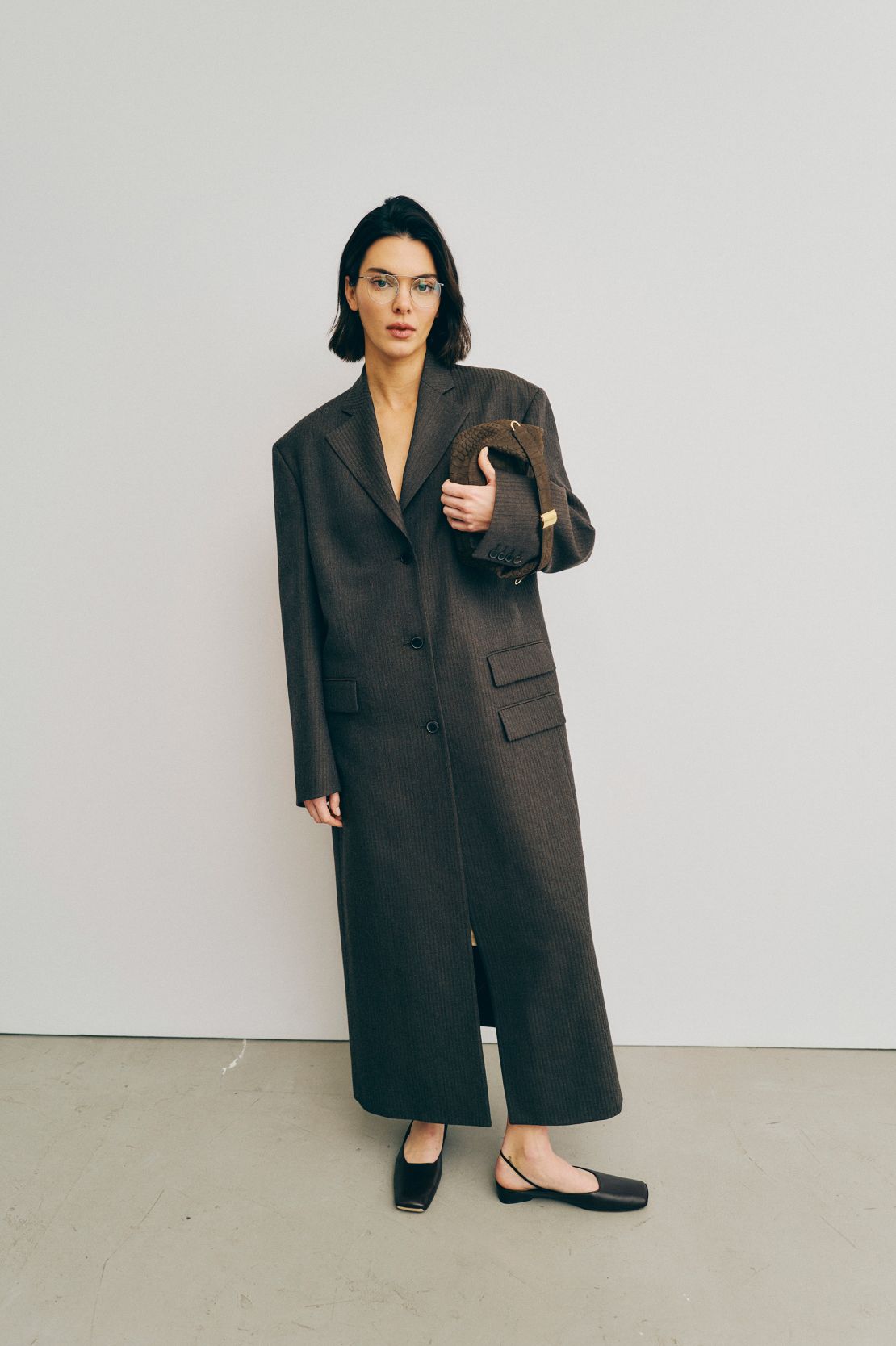 Kendall Jenner backstage bij Calvin Klein in een oversized jas met één borsten met dubbele zakdetails.