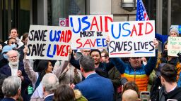 Protesters hold signs in front of the USAID headquarters on February 3, 2025, in Washington, DC.
