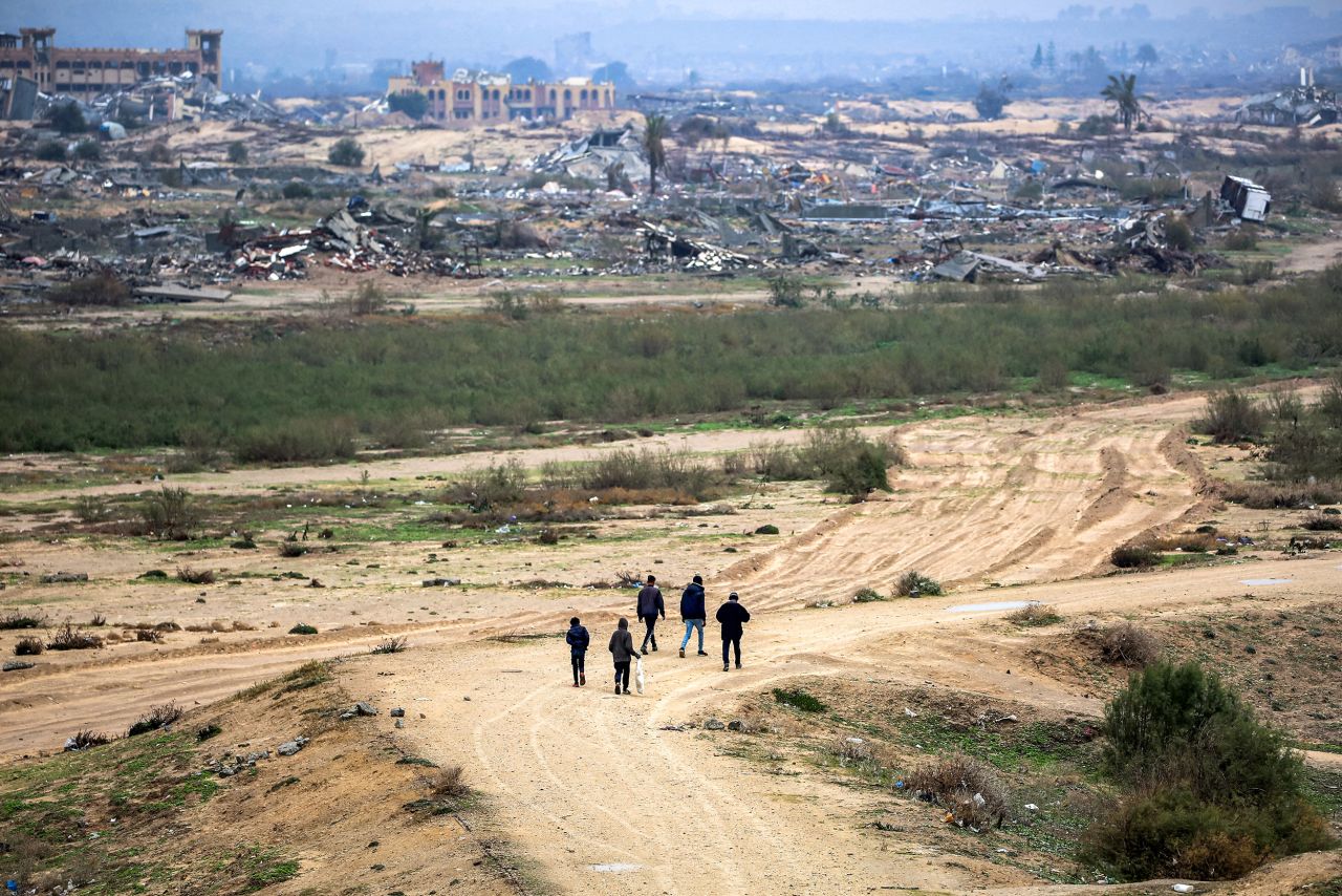 People walk by destroyed buildings near Nuseirat in the Gaza Strip on February 10.