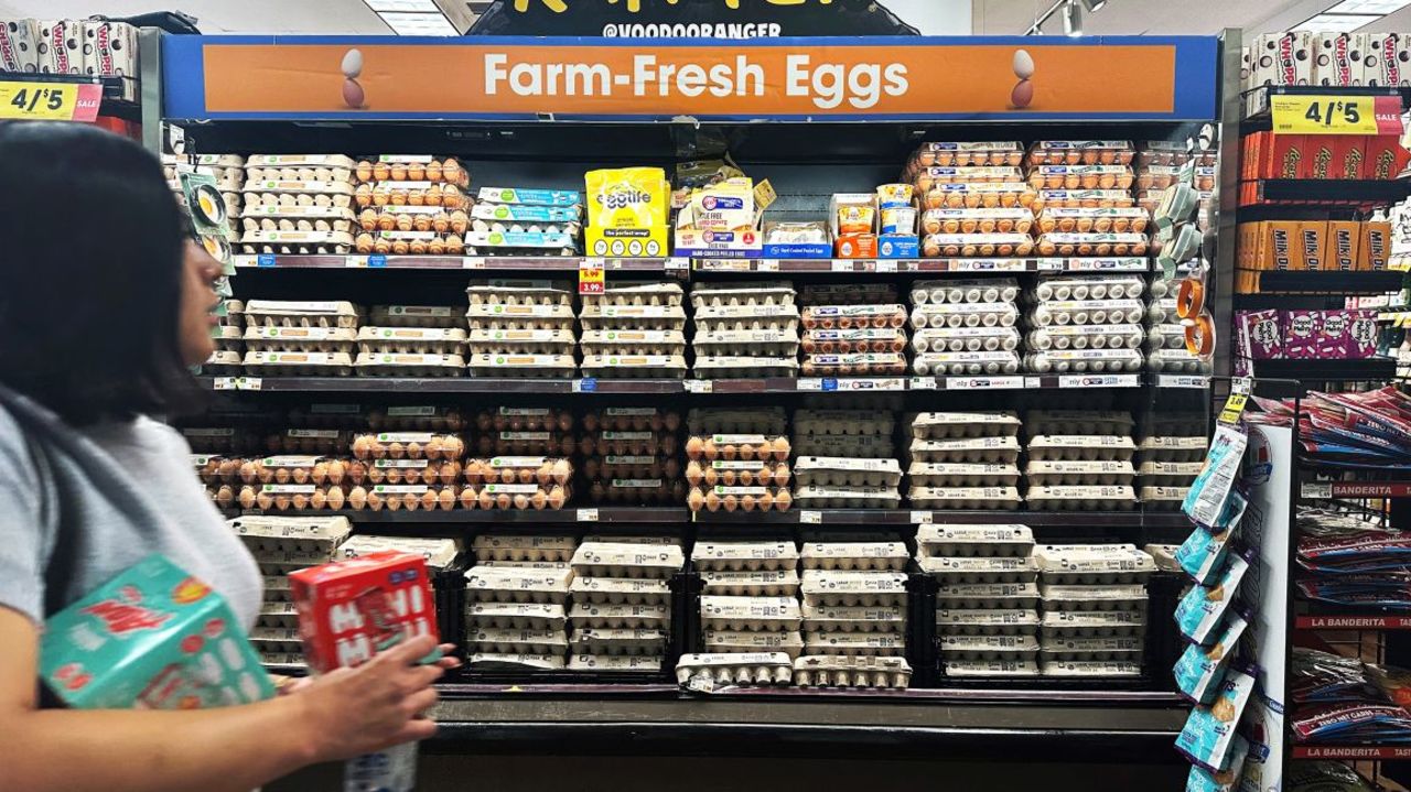 Una compradora de supermercado pasa junto a una exposición de huevos a la venta.