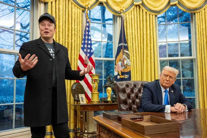 Elon Musk speaks about his federal cost-cutting efforts as President Donald Trump looks on in the Oval Office of the White House on February 11, 2025.