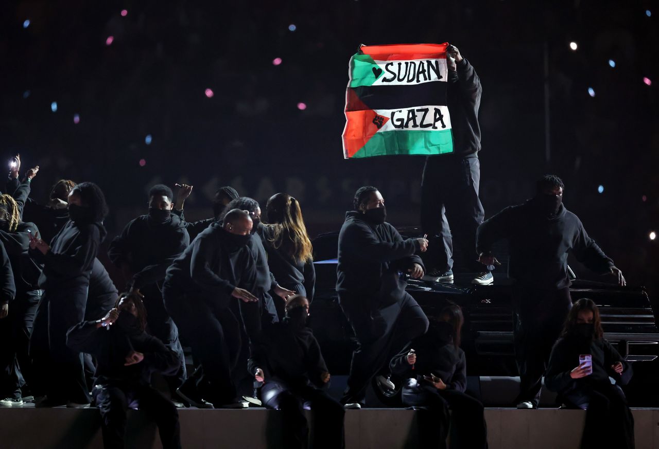 Un manifestante sostiene una bandera en el escenario durante el espectáculo de medio tiempo.
