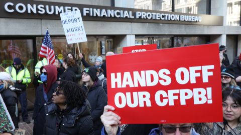 Demonstrators raise signs and posters during a rally outside the Consumer Financial Protection Bureau headquarters in Washington, DC, on February 10, 2025.