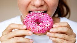 Close-up of a woman eating a donut with pink glaze.