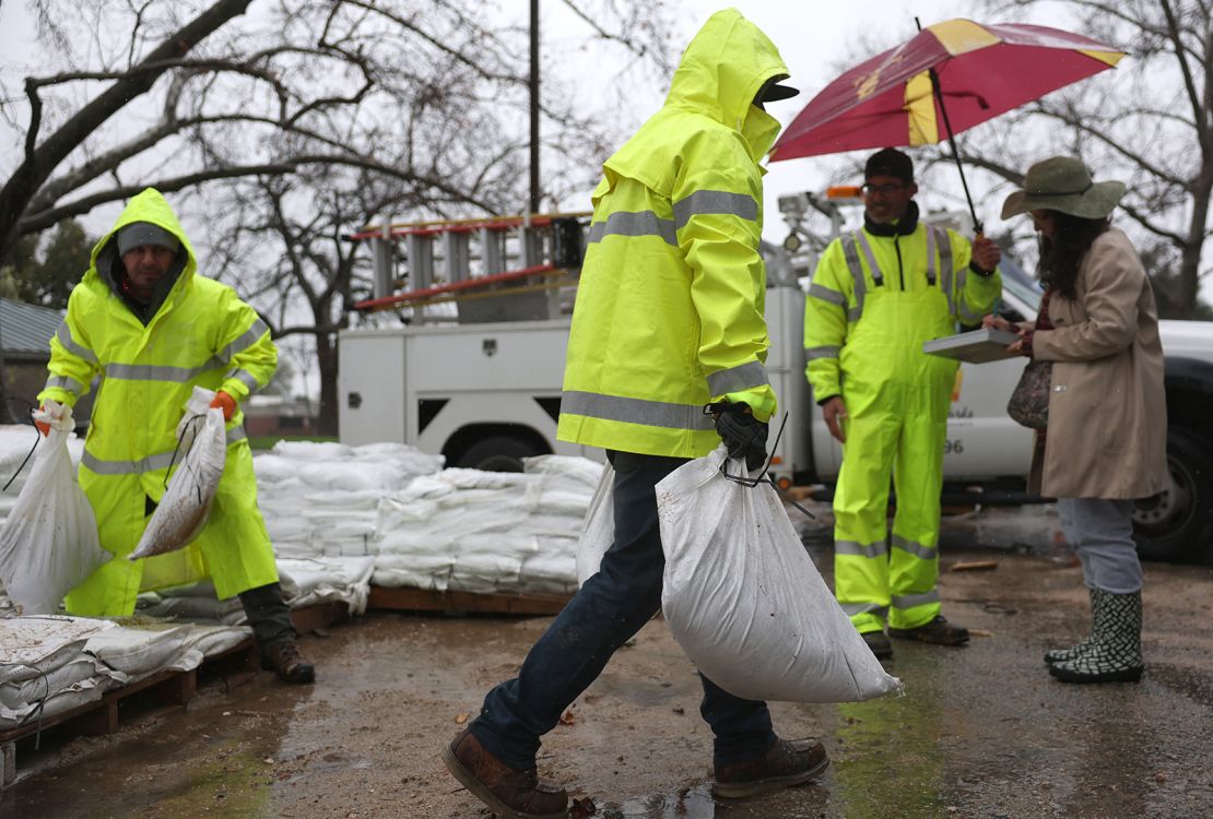 Los Angeles County workers load sandbags in Pasadena, California, for a resident near the Eaton Fire burn zone as a powerful atmospheric river impacts the region Thursday.