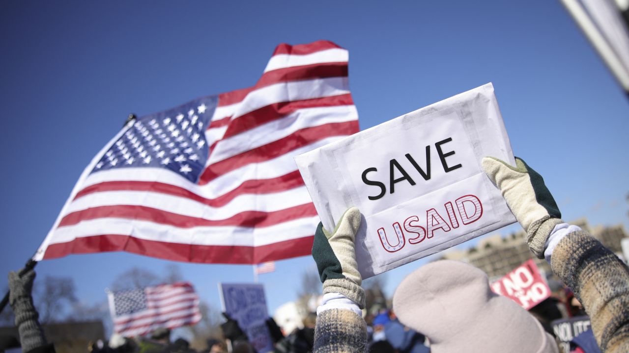 A demonstrator holds a sign reading "Save USAID" during a protest against Project 2025 and the Trump istration at the Capitol Reflecting Pool near the U.S. Capitol in Washington, D.C. on February 17, 2025. (Photo by Bryan Dozier / Middle East Images / Middle East Images via AFP) (Photo by BRYAN DOZIER/Middle East Images/AFP via Getty Images)          