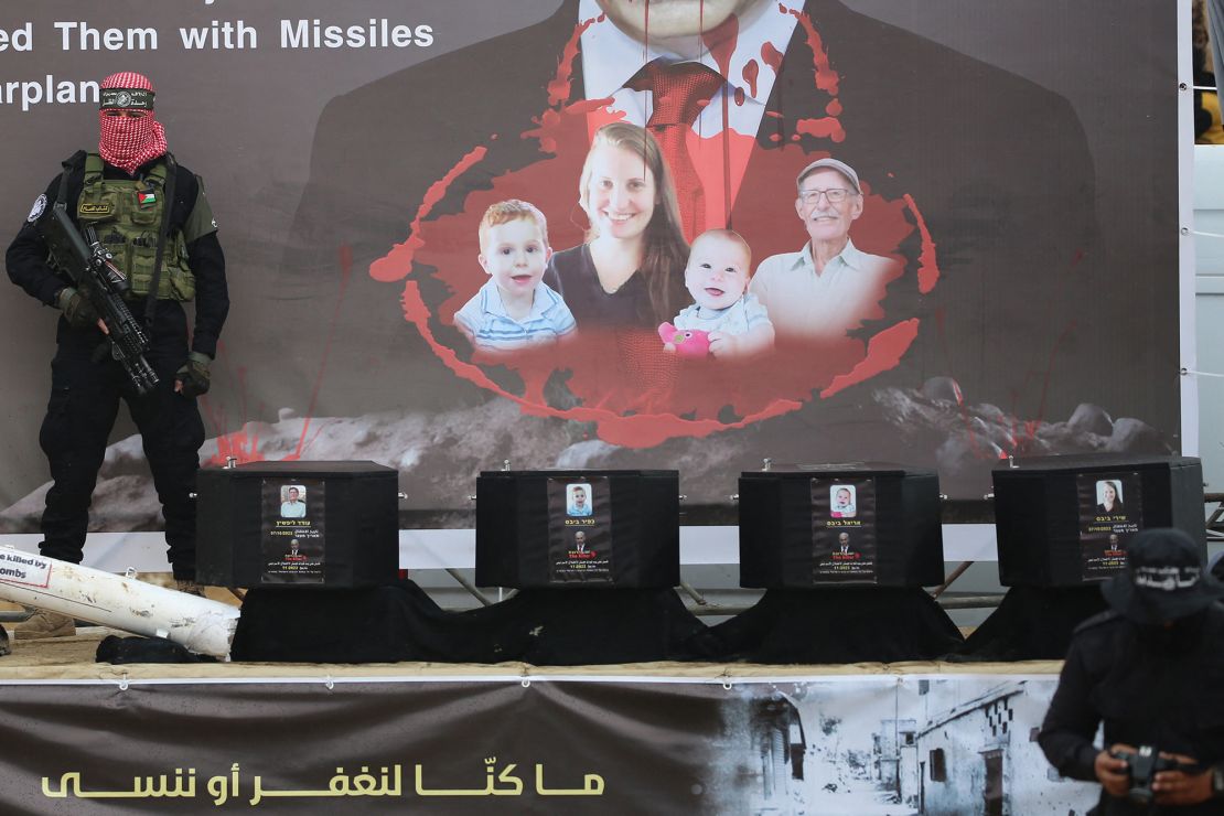 A Hamas militant stands on a stage next to four coffins that were handed over to Israel on Thursday.