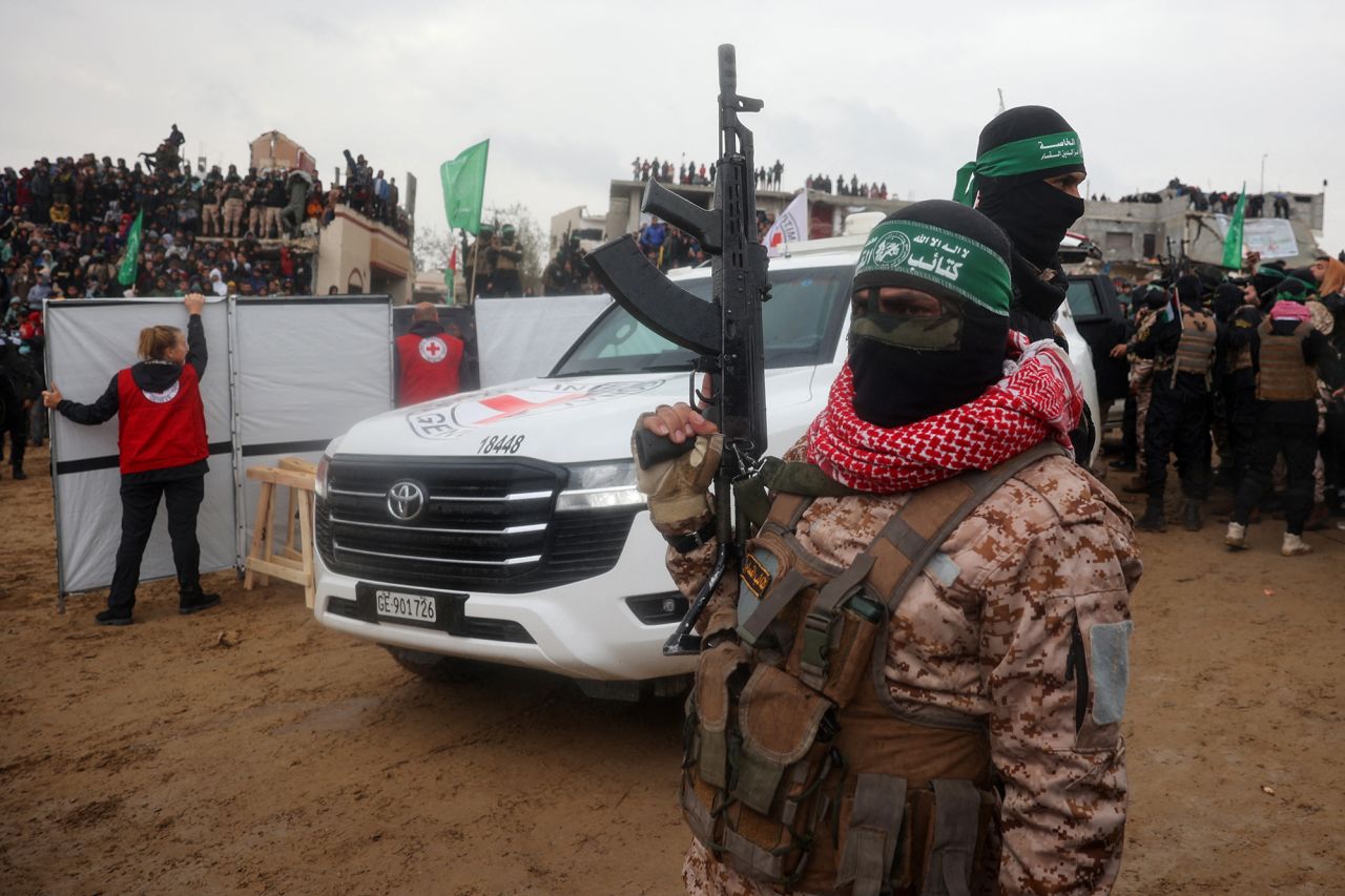 A Hamas fighter stands guard as Red Cross vehicles arrive at the site where four coffins were handed over to Israel, in Khan Yunis, in southern Gaza, on Thursday.