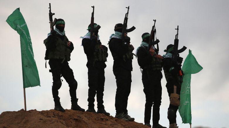 TOPSHOT - Palestinian Hamas militants gather at the site of the handing over of the bodies of four Israeli hostages in Khan Yunis in the southern Gaza on February 20, 2025. Hamas handed over the bodies of four hostages on February 20, including those of the Bibas family, who have become symbols of the hostage crisis that has gripped Israel since the Gaza war broke out. The transfer of the bodies is the first such handover of remains by Hamas since its October 7, 2023 attack on Israel triggered the war. (Photo by Eyad BABA / AFP) (Photo by EYAD BABA/AFP via Getty Images)          