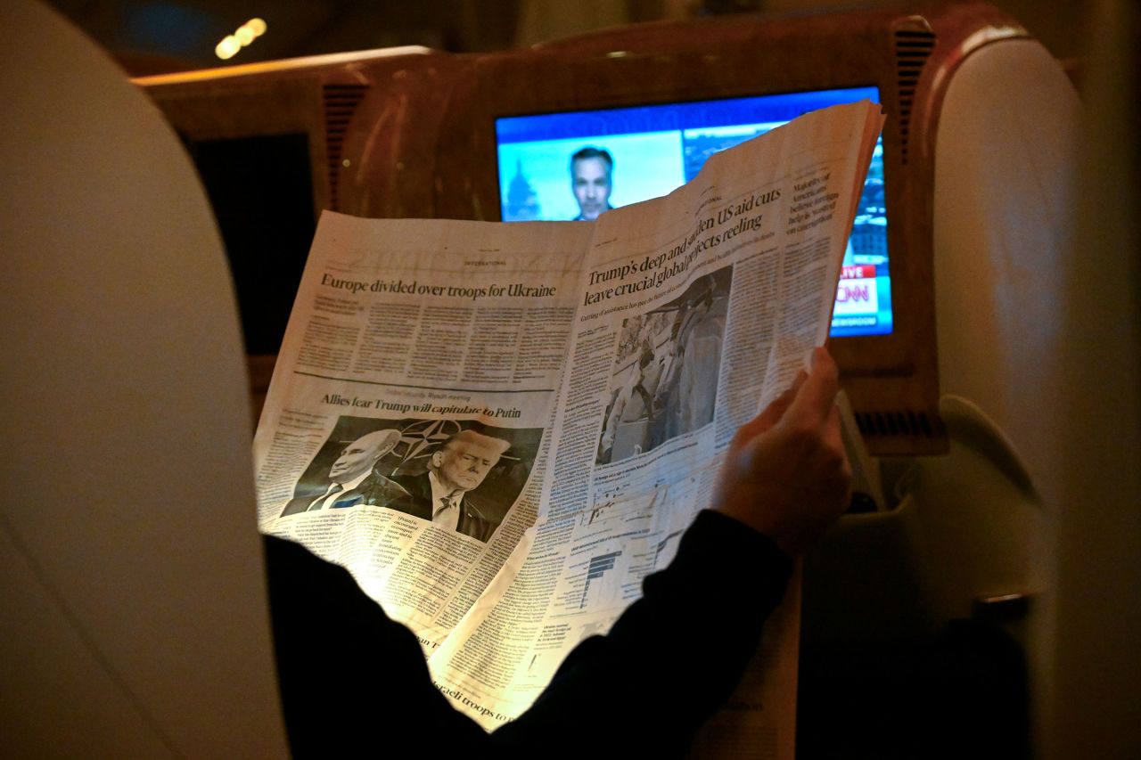 A passenger reads a newspaper story on US President Donald Trump and Russian President Vladimir Putin onboard an Emirates flight to Dubai, United Arab Emirates, on Wednesday.