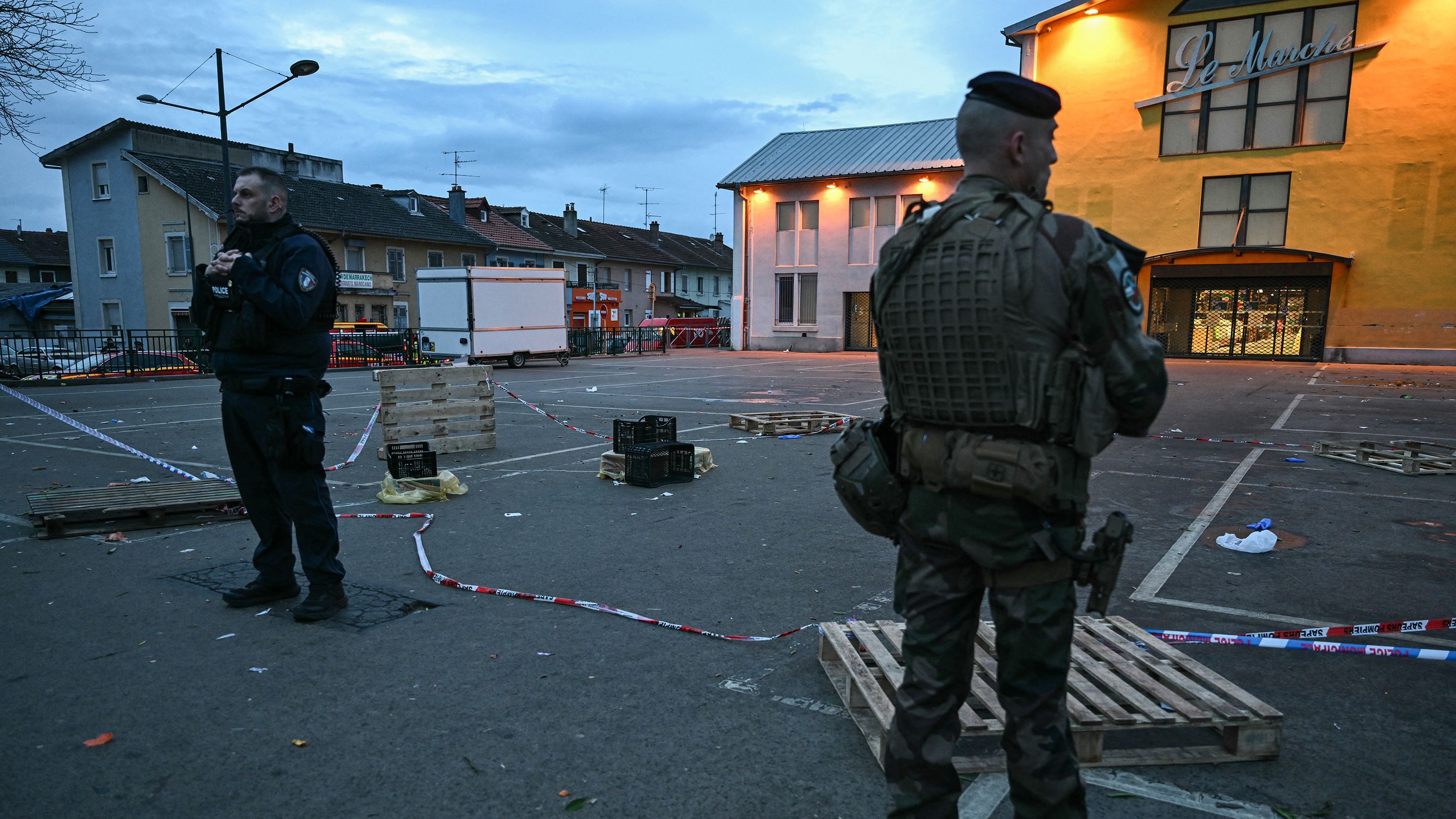 A police officer and a military officer stand guard at the site of a bladed weapon attack where a man is suspected of killing one person and wounding two municipal police officers in Mulhouse, eastern France on February 22, 2025.