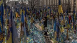 TOPSHOT - Visitors stand next to a makeshift memorial paying tribute to Ukrainian and foreign fighters with flags at the Independence Square in Kyiv, on February 23, 2025, ahead of the third anniversary of Russia's invasion of Ukraine. (Photo by Roman PILIPEY / AFP) (Photo by ROMAN PILIPEY/AFP via Getty Images)          