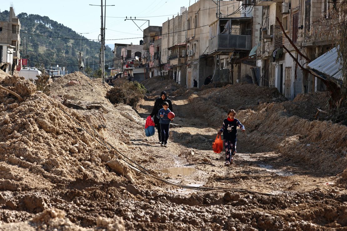 People cross a destroyed street while fleeing the Nur Shams camp for Palestinian refugees near Tulkarem in the occupied West Bank on February 26, 2025.