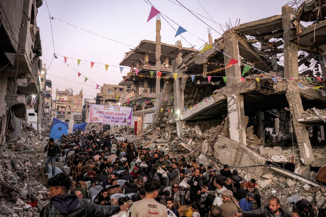 People gather for the Iftar, or fast-breaking meal, on the first day of the Muslim holy fasting month of Ramadan in Jabalya in the northern Gaza Strip on March 1, 2025, by the rubble of collapsed buildings.