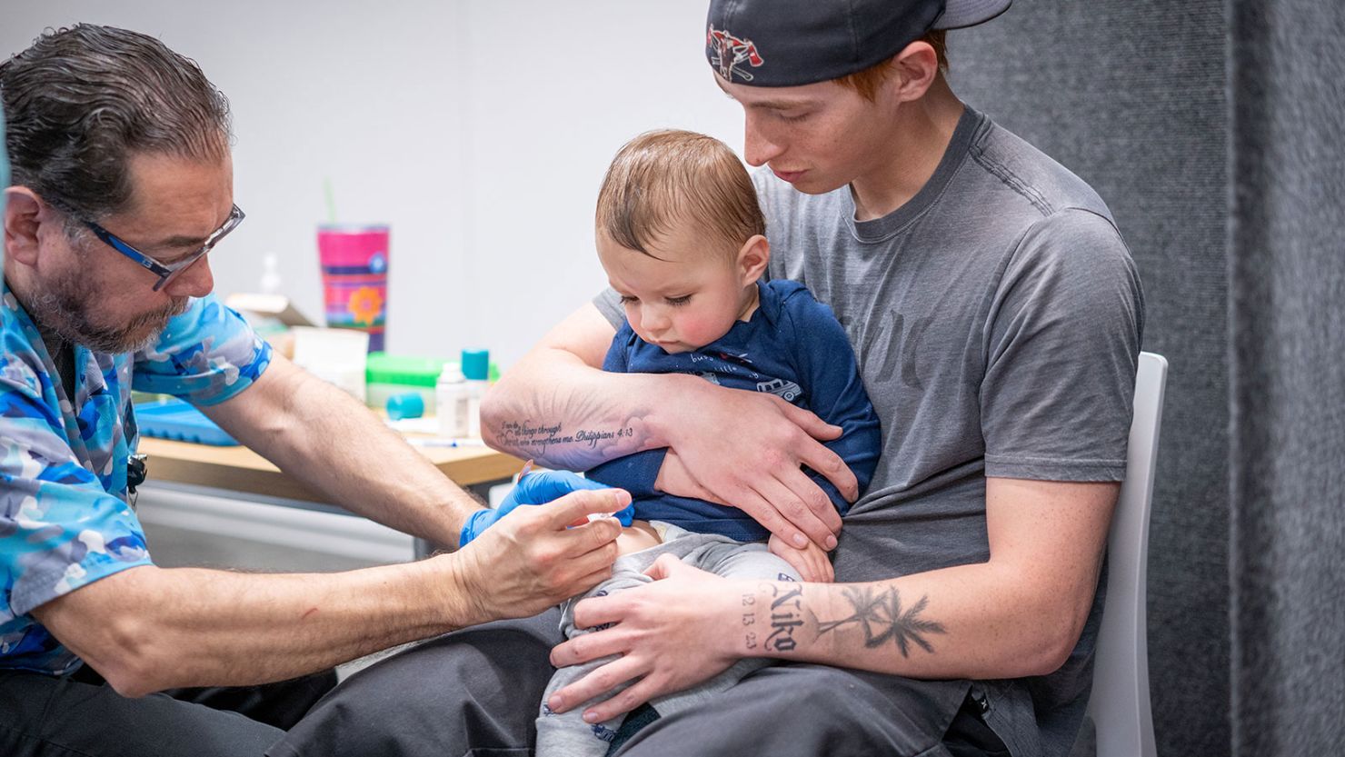 Ethan Turner holds his 14-month-old son, Niko, while he gets the MMR vaccine from Raynard Covarrubio at a vaccine clinic put on by Lubbock Public Health on March 1.