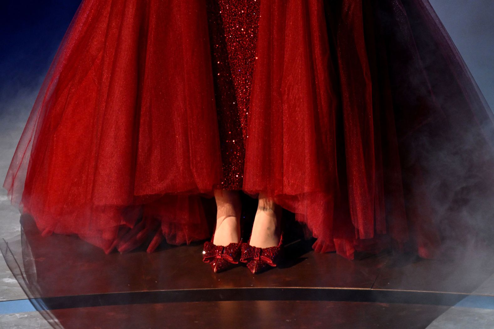 Ariana Grande wears ruby red shoes as she performs "Over the Rainbow" at the start of the show.