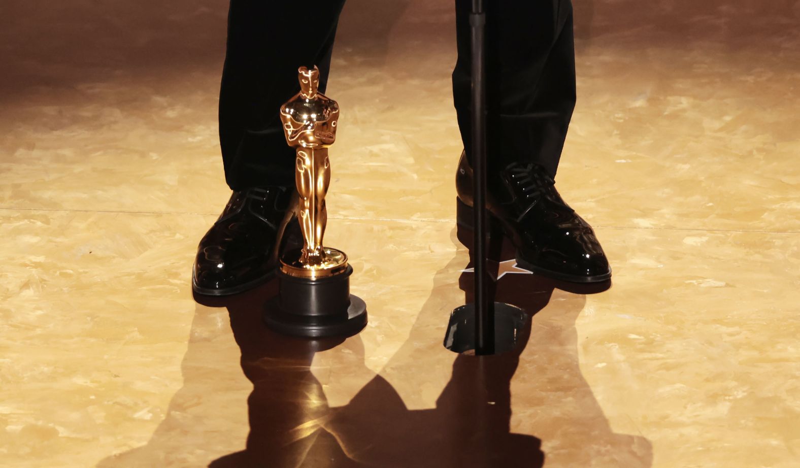 An Oscar is seen at the feet of Baker, who won best director for "Anora."