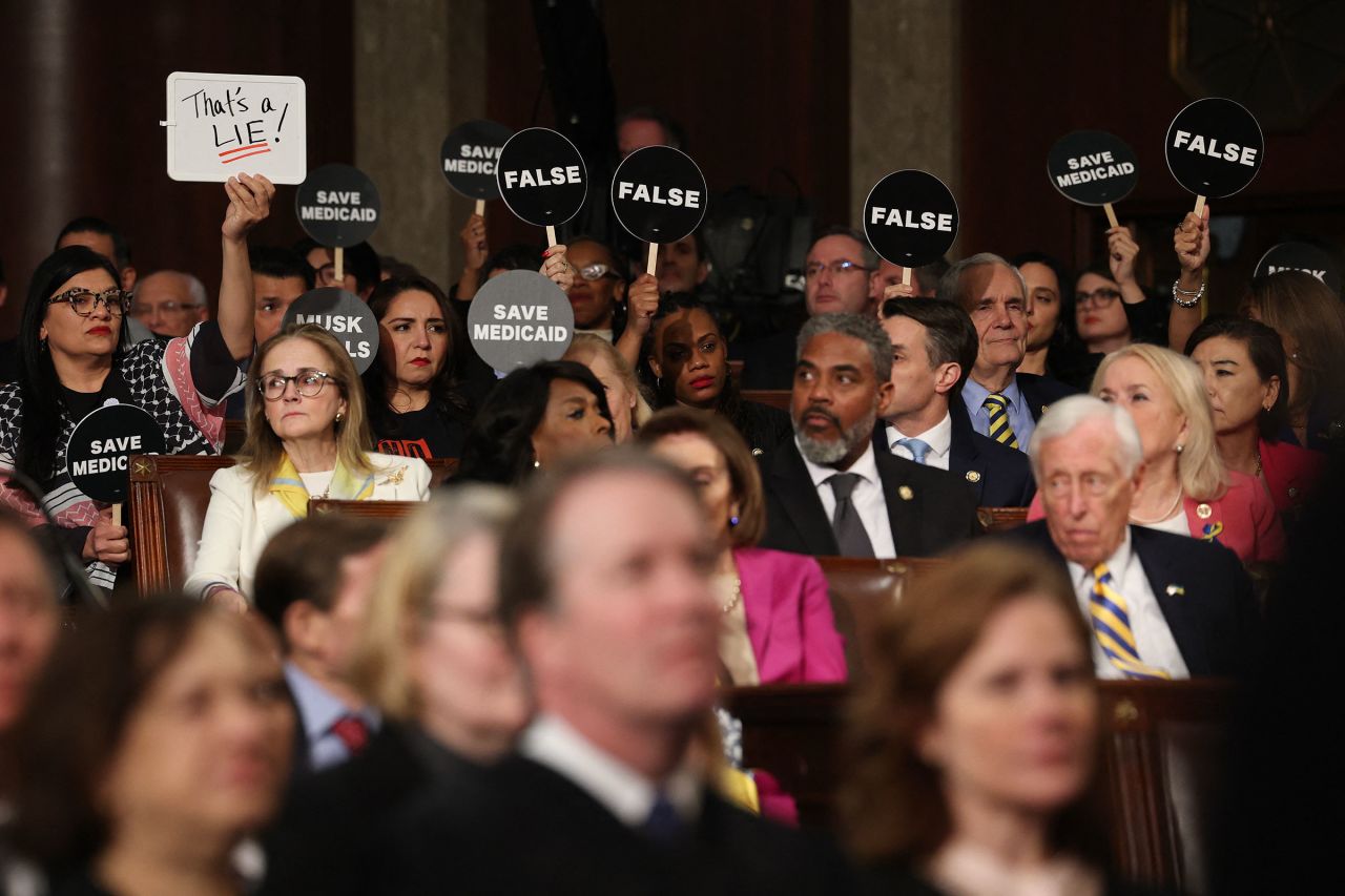 Democrats hold protest signs as President Donald Trump delivers a joint address to Congress on Tuesday.