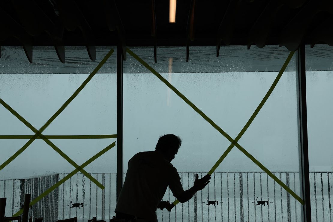 An owner tapes the windows of his café to prevent them from shattering as the outer fringe of Tropical Cyclone Alfred started whipping eastern Australia, at Point Danger in Coolangatta on March 6, 2025.