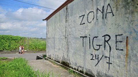 EDITORS NOTE: Graphic content / People walk past a house with graffiti reading "Tiger Zone," referring to the gang that controls the sector, known as 'Los Tiguerones,' in the neighborhood where at least 22 people were killed on the eve in Guayaquil, Ecuador, on March 7, 2025. Rival factions of an Ecuadoran drug trafficking gang fought Thursday in the violent port city of Guayaquil, leaving at least 22 people dead, officials said. (Photo by MARCOS PIN / AFP) (Photo by MARCOS PIN/AFP via Getty Images)