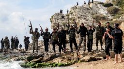 Members of security forces loyal to the interim Syrian government pose together with their firearms as they stand along a rocky beach by the Mediterranean sea coast in Syria's western city of Latakia on March 9, 2025. Syria's interim President Ahmed al-Sharaa called for national unity and peace on March 9, amid growing international backlash following the killing of civilians along the country's coast in the worst violence since the overthrow of former president Bashar al-Assad, in the heartland of the Alawite minority to which the latter belongs. (Photo by OMAR HAJ KADOUR / AFP) (Photo by OMAR HAJ KADOUR/AFP via Getty Images)