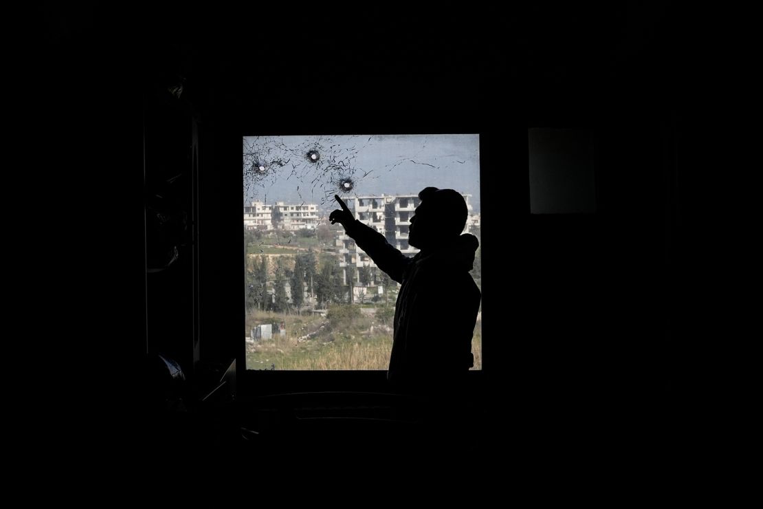 A Syrian man points at bullet holes in a window of a hospital in Jableh town, 25 km south of Latakia, on March 10, 2025, following a spate of violence between Syrian security forces and insurgents loyal to deposed president Bashar al-Assad.