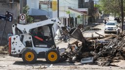 A backhoe excavator moves the debris on a street during the cleaning process in Bahia Blanca, 600 km south of Buenos Aires on March 10, 2025. The severe rainfall left at least sixteen dead and triggered mass evacuations, inundated hospitals, and caused sections of asphalt to collapse. Rescuers continue Monday to search for survivors of the unprecedented storm that flooded the Argentine city of Bahia Blanca, hit by fierce rains that left 16 dead, hundreds missing, and millions of dollars in losses. (Photo by PABLO PRESTI / AFP) (Photo by PABLO PRESTI/AFP via Getty Images)          