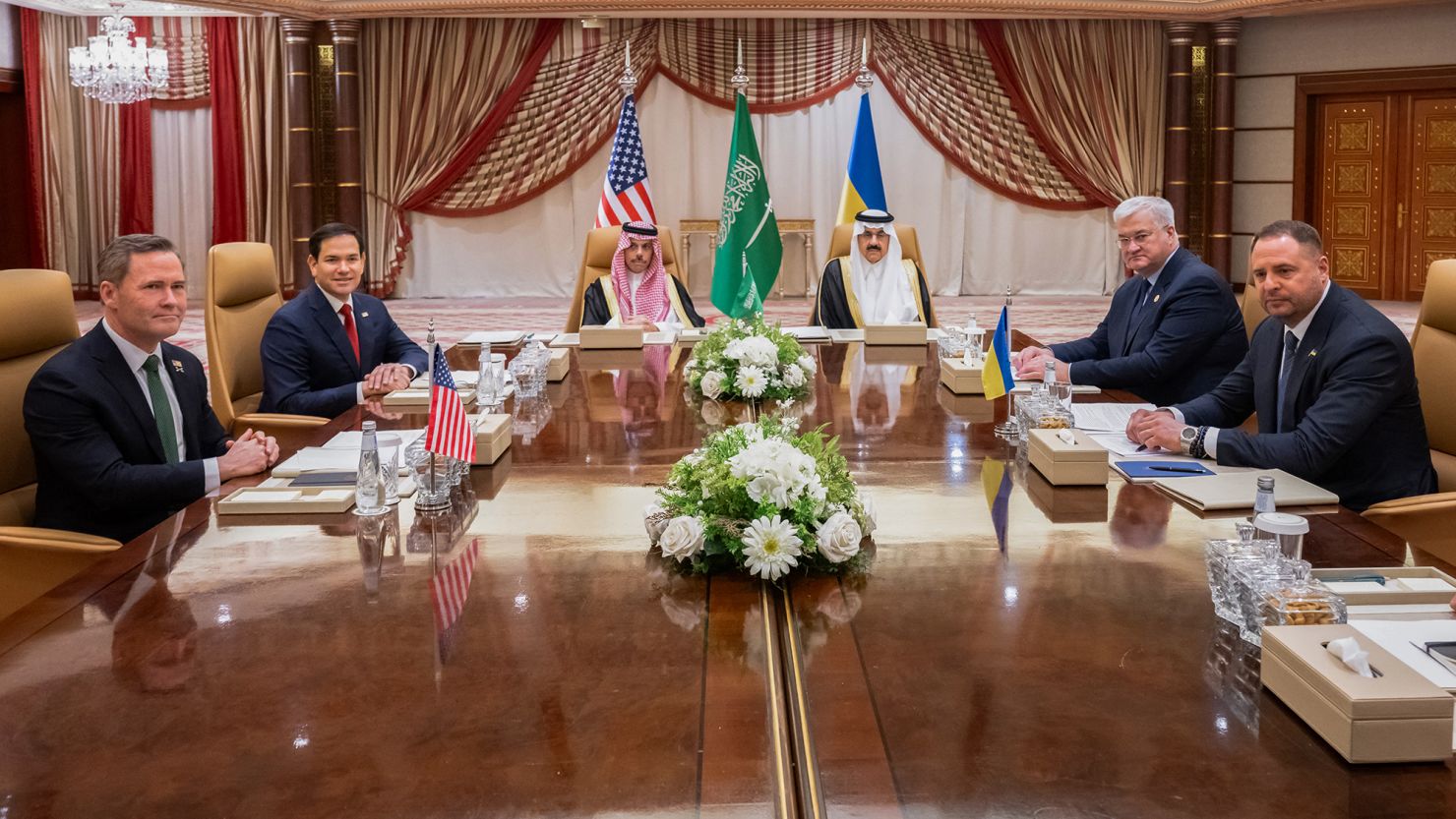 several men sitting around a table with flags and flowers