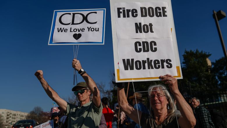 Demonstrators protesting personnel cuts at the Centers for Disease Control hold signs outside the organization's  headquarters in Atlanta on March 12, 2025.