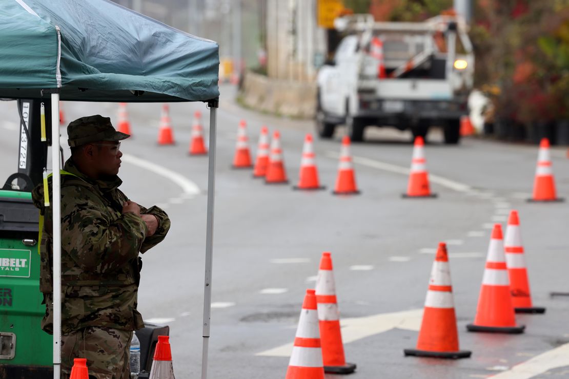 A member of the California National Guard monitors a checkpoint on Pacific Coast Highway, at Chautauqua Boulevard, minutes before it was shutdown in Santa Monica on March 12, 2025. Caltrans closed a segment of Pacific Coast Highway to residents and businesses in burn scar areas at noon Wednesday due to safety concerns from the incoming storm.