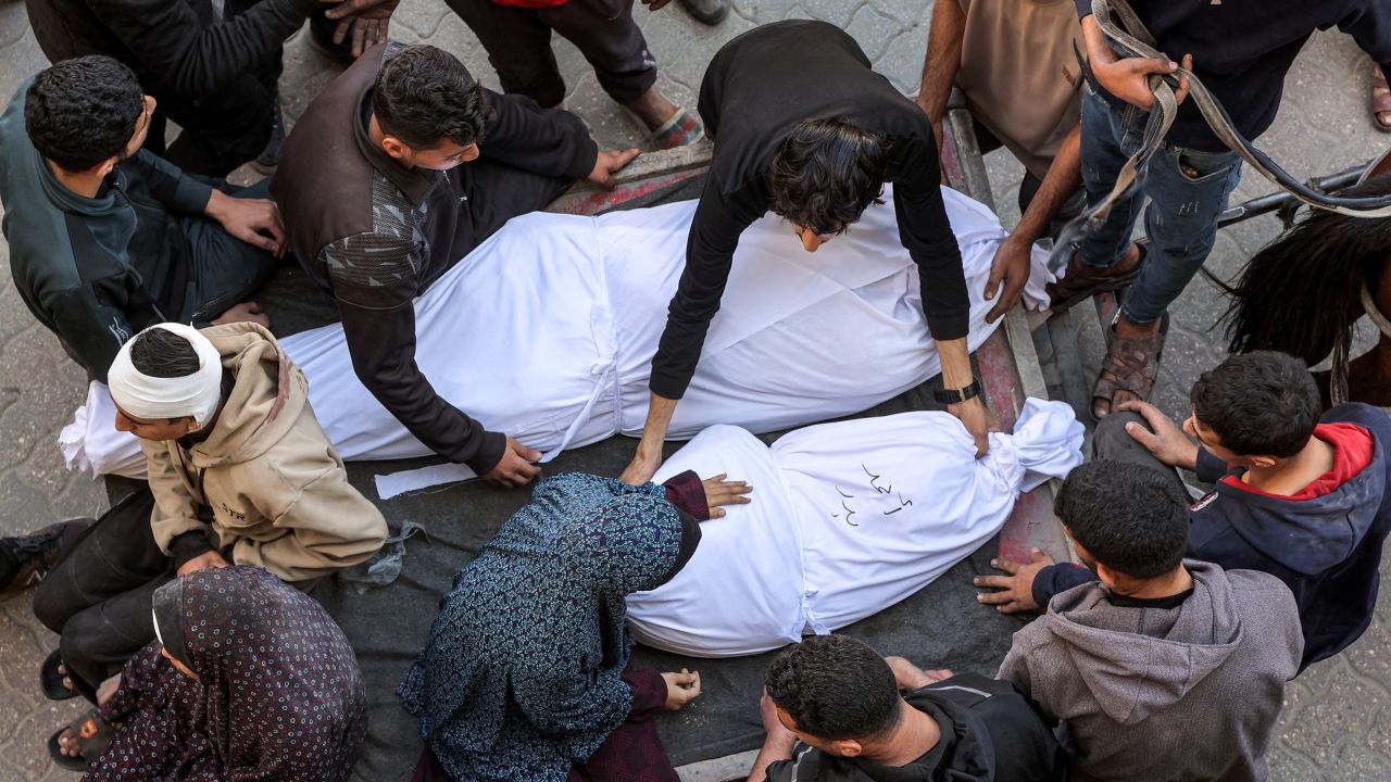 EDITORS NOTE: Graphic content / A woman sits by as a man places the shrouded body of one of the victims killed in Israeli bombardment in the bed of a horse-drawn cart at the Ahli Arab hospital, also known as the Baptist hospital, in Gaza City on March 18, 2025. Israel on March 18 unleashed its most intense strikes on the Gaza Strip since a January ceasefire, with rescuers reporting 220 people killed, and Hamas accusing Benjamin Netanyahu of deciding to "resume war" after a deadlock on extending the truce. (Photo by Omar AL-QATTAA / AFP) (Photo by OMAR AL-QATTAA/AFP via Getty Images)          