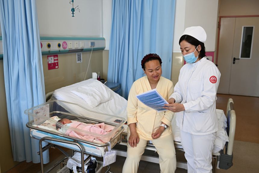 A medical worker explains local childcare subsidies at a hospital on March 16, 2025 in Hohhot, Inner Mongolia of China.
