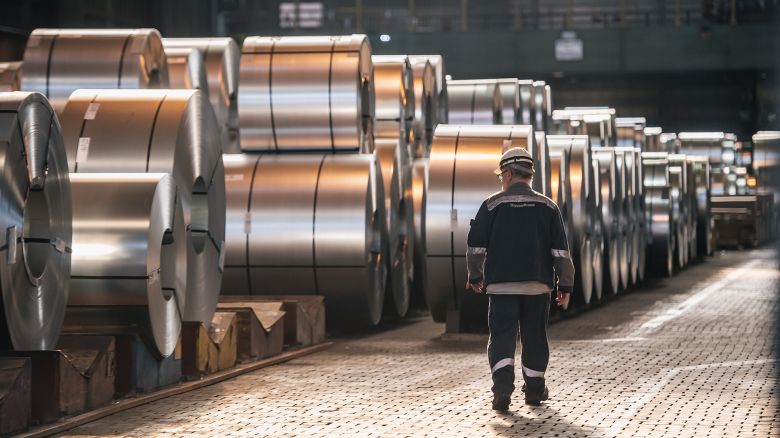 A worker walks past coils of finished steel at the Thyssenkrupp steel mill on March 20 in Duisburg, Germany.