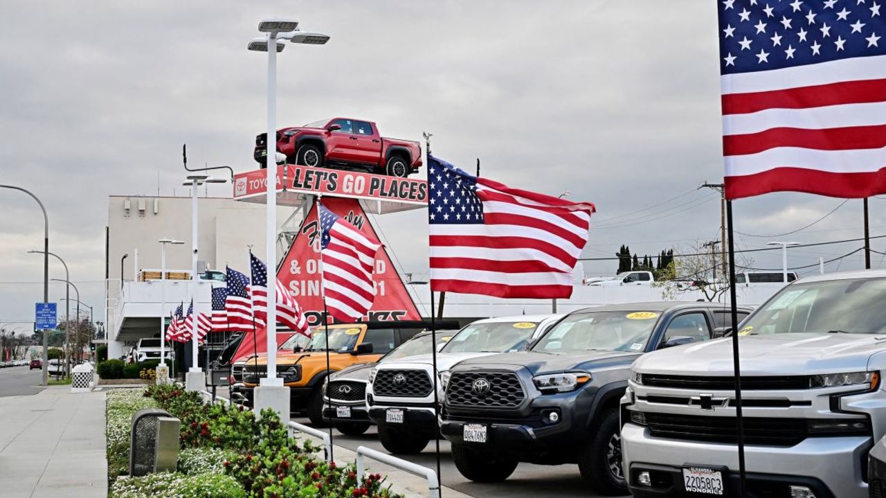 Banderas estadounidenses ondean frente a un concesionario de automóviles en Alhambra, California, el 27 de marzo de 2025, después de que el presidente Donald Trump anunciara aranceles a la importación de vehículos y repuestos.