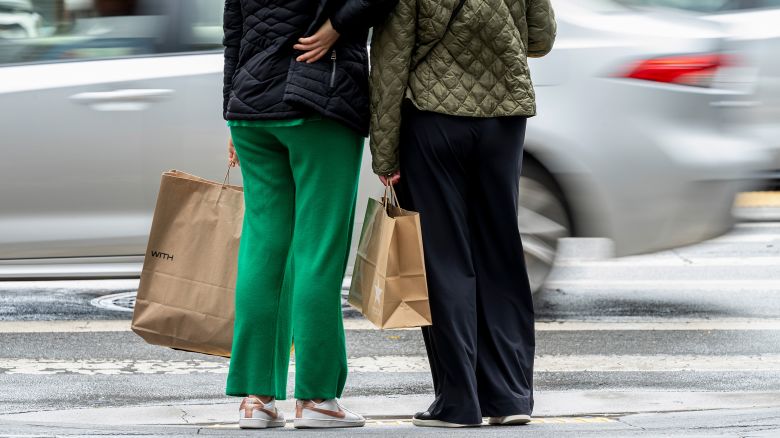 Shoppers hold bags while waiting to cross Post Street in San Francisco on March 27.
