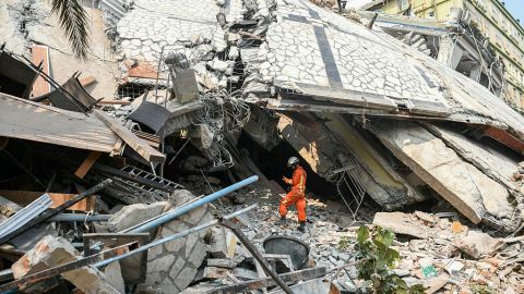 TOPSHOT - A rescue worker stands on rubble as teams attempt to free trapped residents at the destroyed Sky Villa Condominium development in Mandalay on March 29, 2025, a day after an earthquake struck central Myanmar. More than 90 people could be trapped inside the crushed remains of an apartment block in Mandalay in central Myanmar destroyed by a devastating earthquake, a Red Cross official told AFP on March 29 as rescuers worked to free the victims. (Photo by Sai Aung MAIN / AFP) (Photo by SAI AUNG MAIN/AFP via Getty Images)