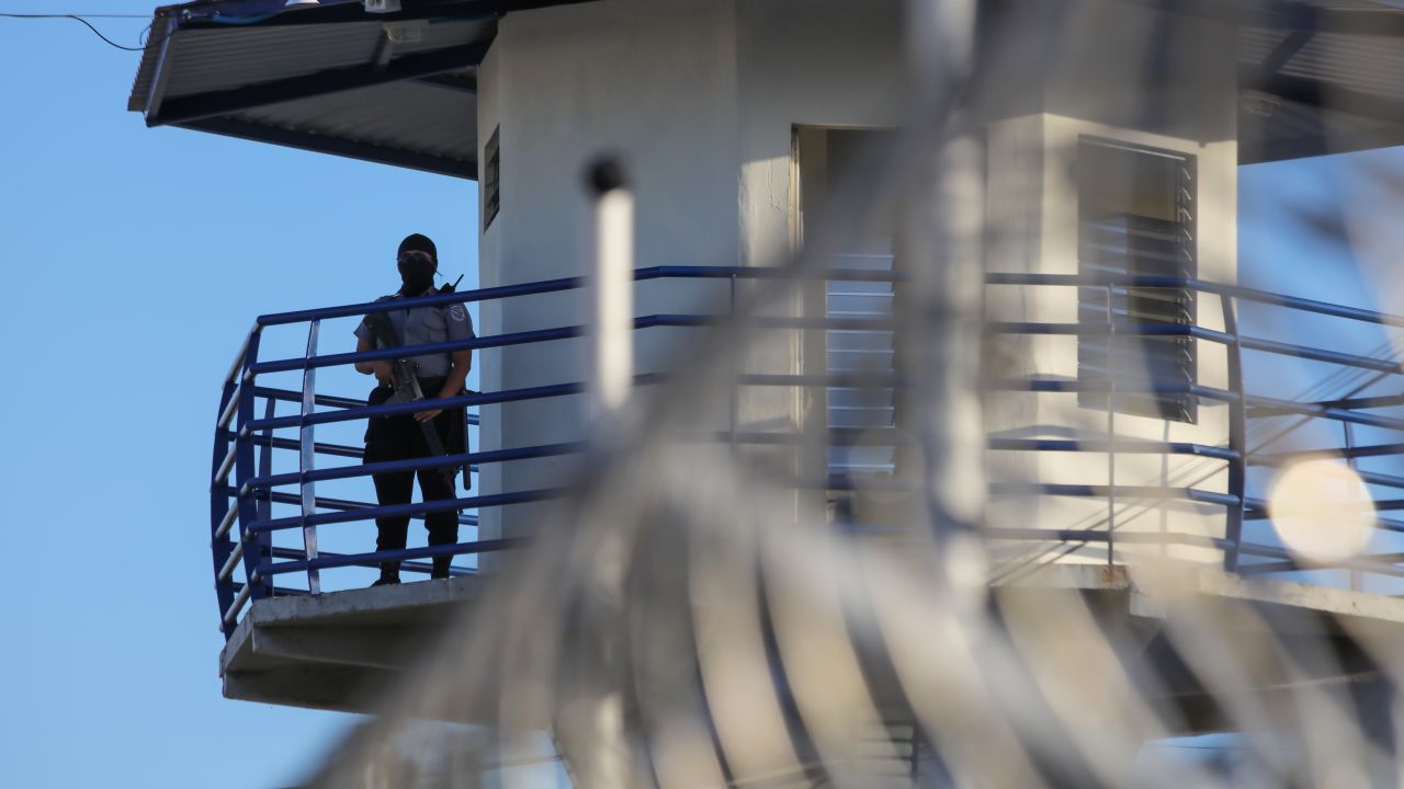 Un funcionario de prisiones vigila la torre de vigilancia del centro penitenciario de máxima seguridad CECOT el 4 de abril de 2025 en Tecoluca, San Vicente, El Salvador.