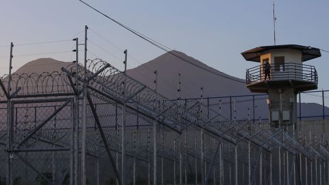 Un oficial de prisiones vigila desde la torre de observación con el volcán San Vicente al fondo en el centro penitenciario de máxima seguridad CECOT (Centro de Alojamiento Obligatorio de Terrorismo) el 4 de abril de 2025 en Tecoluca, San Vicente, El Salvador.
