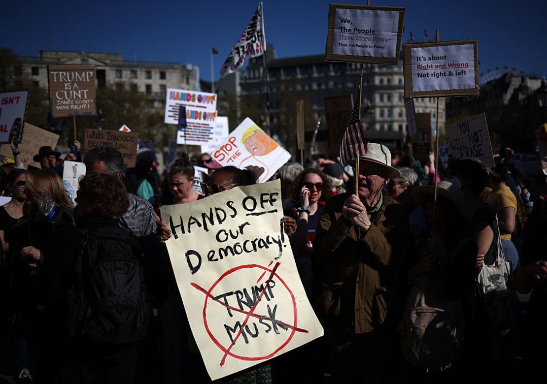 Varias personas sostienen pancartas durante una protesta contra el presidente de Estados Unidos, Donald Trump, y su asesor principal, Elon Musk, en el centro de Londres el 5 de abril de 2025, como parte de un día internacional de protesta llamado «¡Manos fuera!». «¡Manos fuera!» exige «el fin de este acaparamiento de poder multimillonario».