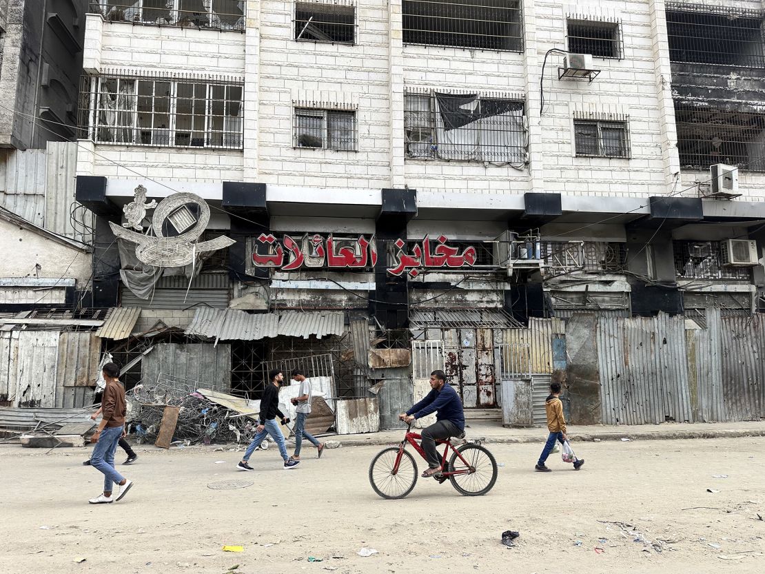 People walk along a street lined with damaged storefronts and a shuttered bakery in northern Gaza on April 1.