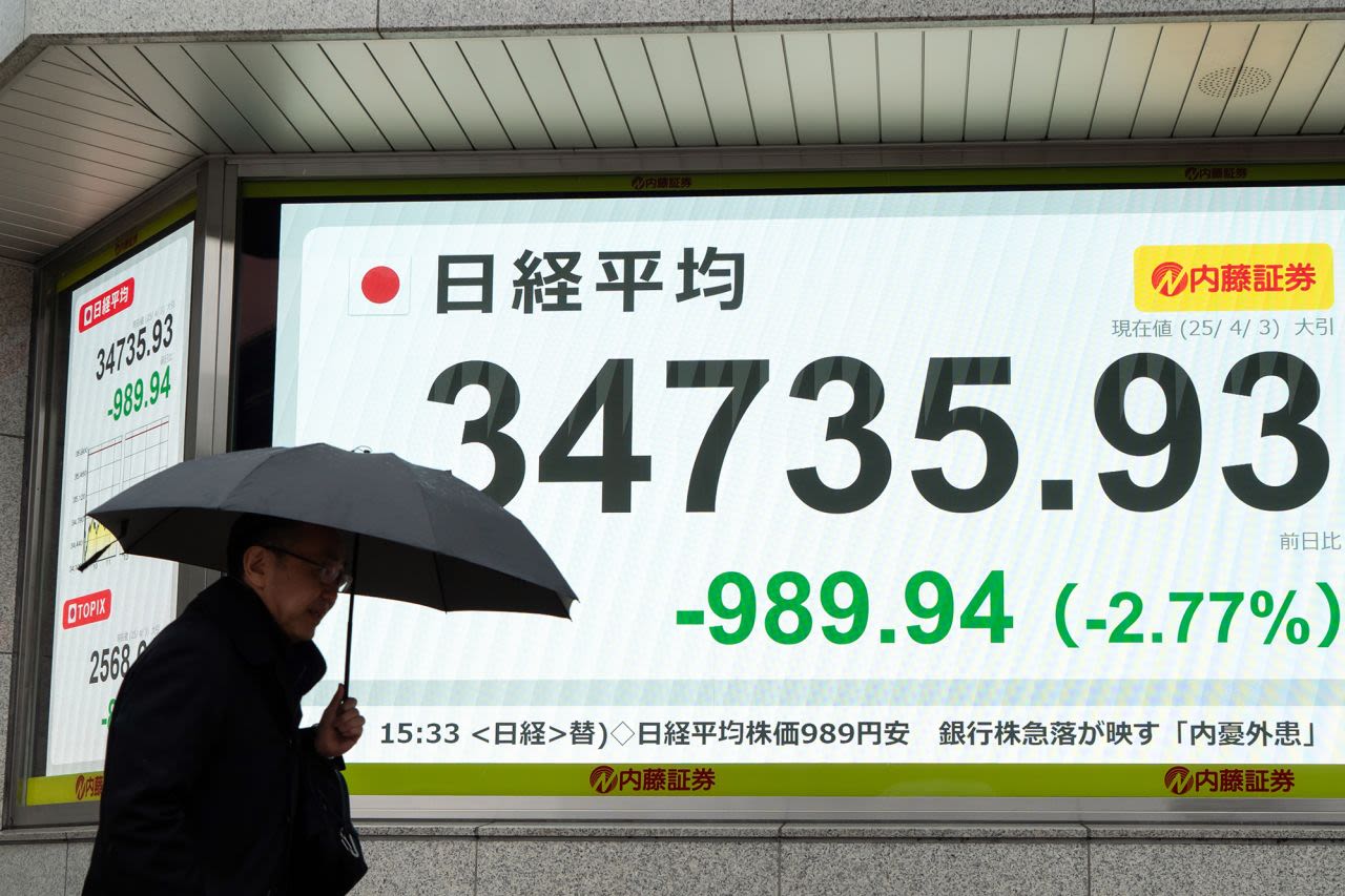 Un peatón camina junto a un tablero electrónico que muestra la cifra de cierre del promedio de acciones Nikkei 225 en Tokio, Japón, el jueves. El Nikkei 225 de Japón cayó a un mínimo de ocho meses.