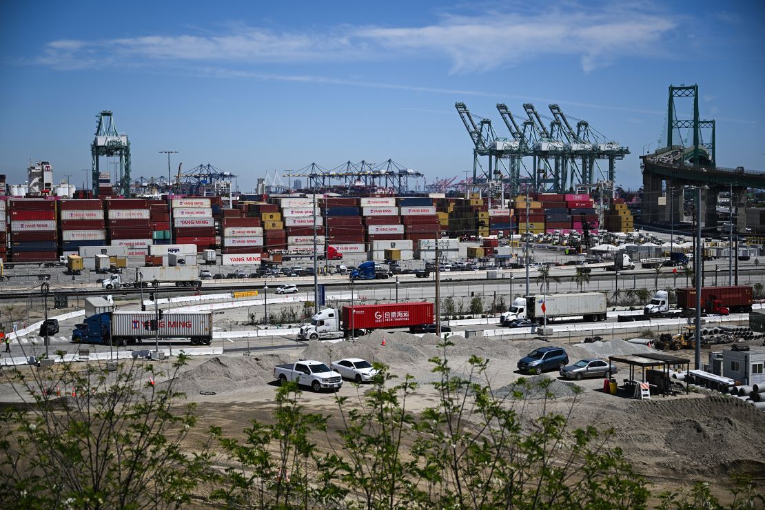 Trucks drive to unload cargo shipping containers as cranes and the Vincent Thomas Bridge stand on the horizon at the Port of Los Angeles in San Pedro, California on April 10.
