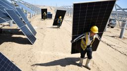 TOPSHOT - Workers carry solar panels to be installed in the desert at the Ningguoyun Lingwu 1 million kilowatt photovoltaic project in Lingwu, in China's northern Ningxia region on April 14, 2025. (Photo by AFP) / China OUT (Photo by STR/AFP via Getty Images)          